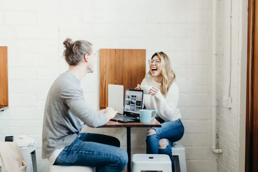 Two people laughing during a laptop meeting.