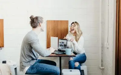 Two people laughing during a laptop meeting.