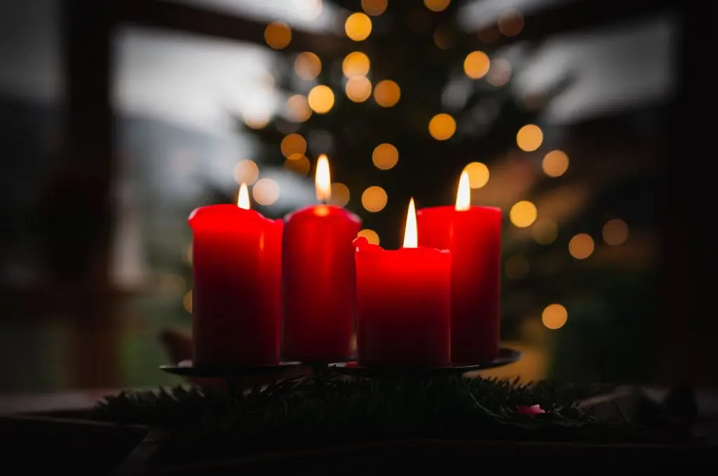Lit red candles with Christmas tree bokeh background.