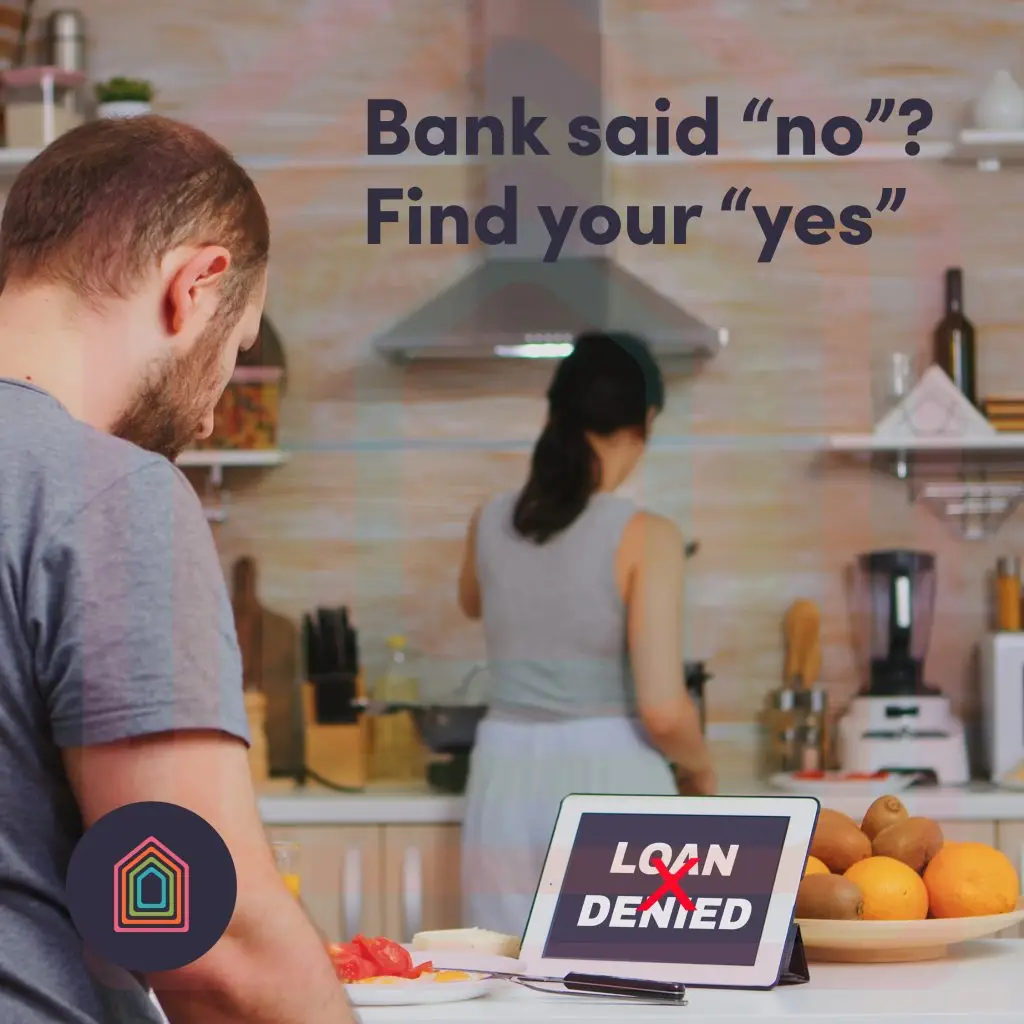 Couple in kitchen with "loan denied" message on tablet.